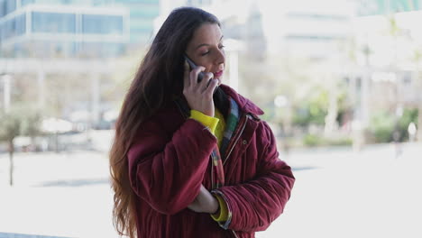 Cheerful-mature-woman-in-maroon-jacket-talking-on-phone-outdoor